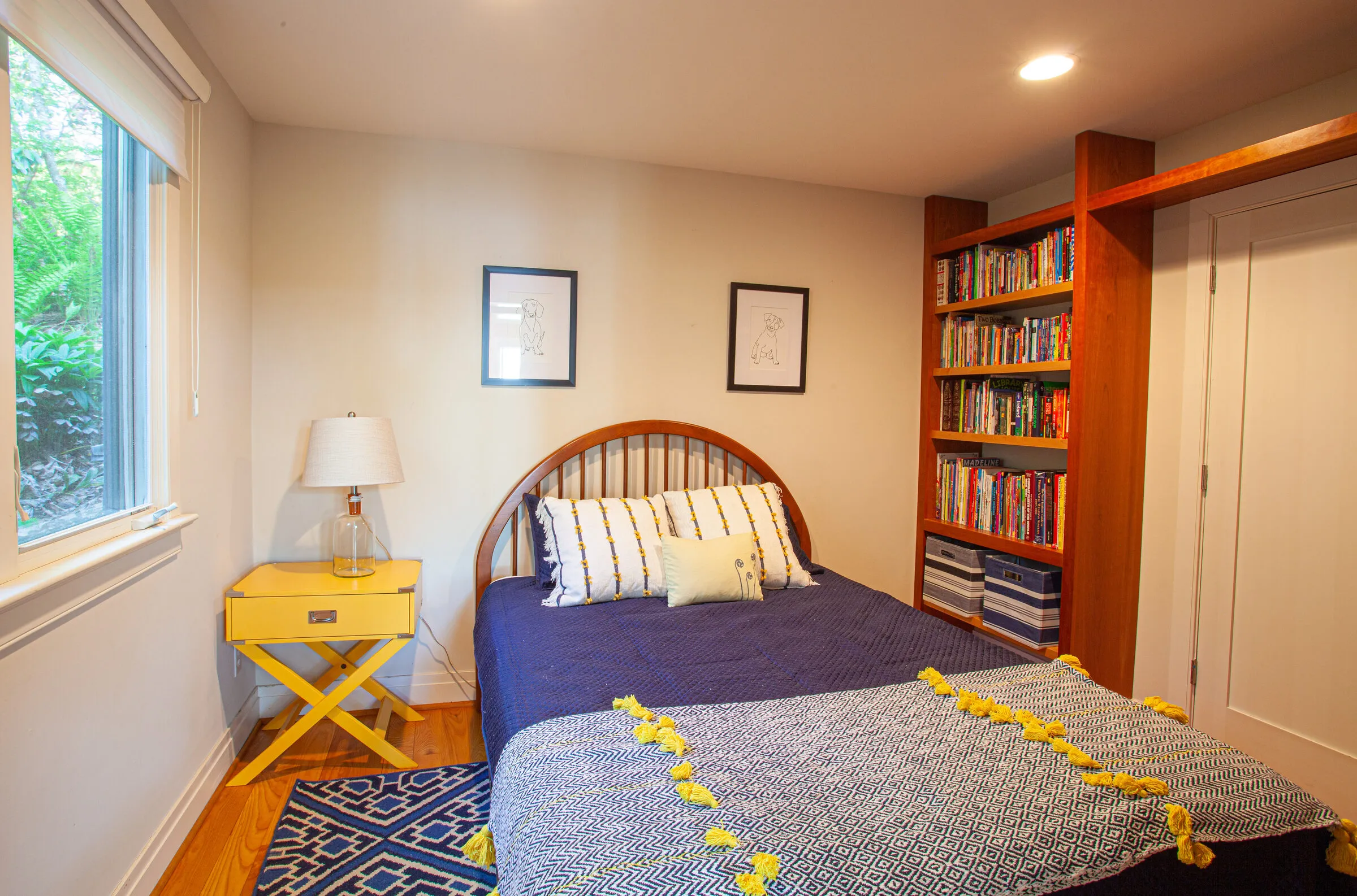Queen bedroom with yellow nightstand and bookshelves